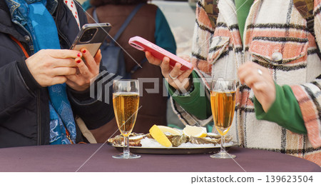 Friends using smartphones while eating oysters at Prague market Friends using smartphones while eating oysters at Prague market 139623504