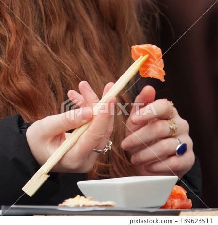 Eating fresh salmon sashimi with wooden chopsticks at Prague Naplavka Eating fresh salmon sashimi with wooden chopsticks at Prague Naplavka 139623511