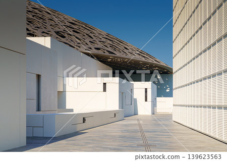 Abu Dhabi, United Arab Emirates - Jan 10 2024, Panoramic view of the snow-white facade of the Louvre Abu Dhabi with a metal dome surrounded by water, at daytime, Abu Dhabi, United Arab Emirates Abu Dhabi, United Arab Emirates - Jan 10 2024, Panoramic view of the snow-white facade of the Louvre Abu Dhabi with a metal dome surrounded by water, at daytime, Abu Dhabi, United Arab Emirates 139623563