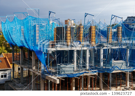 Building construction site with blue safety netting 139623727