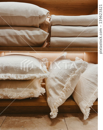Neutral linen pillows and folded blankets on wooden shelves, cozy home textile display with natural textures and warm minimalist decor Neutral linen pillows and folded blankets on wooden shelves, cozy home textile display with natural textures and warm minimalist decor 139623821