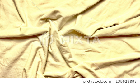crumpled pale yellow fabric twists into deep intricate wrinkles with soft shadows creating serene tactile texture crumpled pale yellow fabric twists into deep intricate wrinkles with soft shadows creating serene tactile texture 139623895