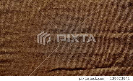 wrinkled brown denim texture reveals authentic organic folds and intricate weave in warm earthy tones 139623941