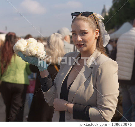 Stylish vendor holding lions mane mushroom among Naplavka market crowd Stylish vendor holding lions mane mushroom among Naplavka market crowd 139623976