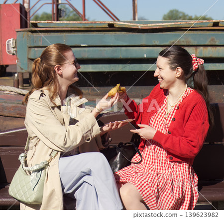Happy female friends sharing street food at Naplavka outdoor market Happy female friends sharing street food at Naplavka outdoor market 139623982