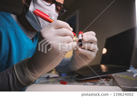Medical professional analyzing blood sample for health research Medical professional analyzing blood sample for health research 139624002