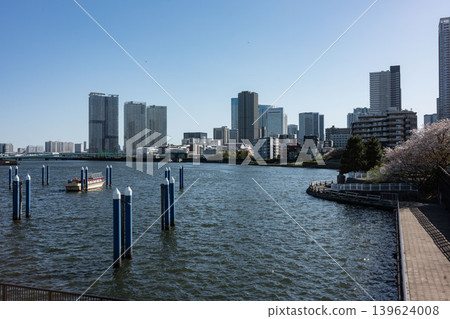 Everyday life on the Tokyo Riverside: A moored houseboat quietly standing with towering apartment buildings in the background. Everyday life on the Tokyo Riverside: A moored houseboat quietly standing with towering apartment buildings in the background. 139624008