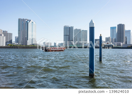 Everyday life on the Tokyo Riverside: A moored houseboat quietly standing with towering apartment buildings in the background. Everyday life on the Tokyo Riverside: A moored houseboat quietly standing with towering apartment buildings in the background. 139624010