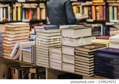 Various book stacks fill large bookstore table with colorful covers and spines. Scene conveys literary abundance, curiosity and bookstore inspiration. Education, school, study, reading fiction concept 139624052