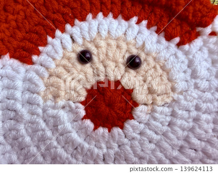 crocheted santa claus face with fluffy beard and red nose radiates jolly festive warmth through cozy handmade yarn crocheted santa claus face with fluffy beard and red nose radiates jolly festive warmth through cozy handmade yarn 139624113
