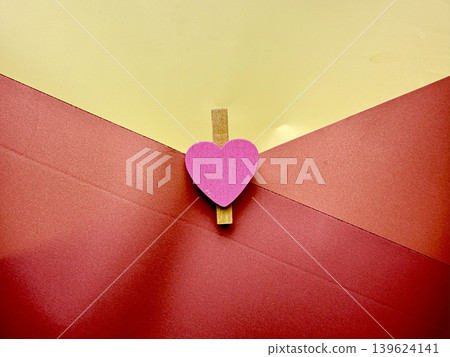 romantic pink wooden heart clothespin clipping vibrant red envelope flap against sunny yellow background romantic pink wooden heart clothespin clipping vibrant red envelope flap against sunny yellow background 139624141