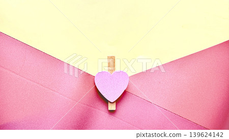 heartfelt romantic pink envelope clipped by purple heart wooden clothespin on vibrant yellow backdrop heartfelt romantic pink envelope clipped by purple heart wooden clothespin on vibrant yellow backdrop 139624142