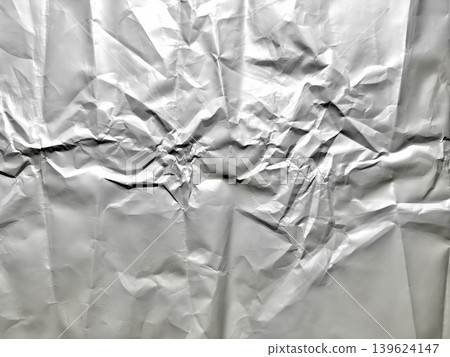 crumpled aluminum foil texture with chaotic creases and gleaming reflections in dramatic high contrast abstract macro 139624147