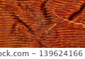 dramatic orange fabric undulates in flowing wavy pleats revealing rich granular texture and golden highlights 139624166