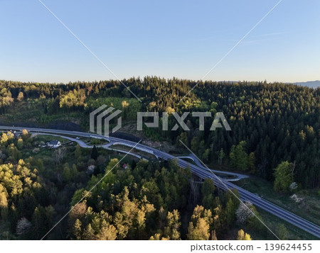 Panoramic Shot Of Winding Highway Weaving Through Dense Woodland Embracing Rural Settlements Panoramic Shot Of Winding Highway Weaving Through Dense Woodland Embracing Rural Settlements 139624455