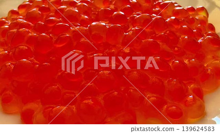 A plate showcasing vibrant red fish caviar, elegantly presented on a pristine white dish 139624583