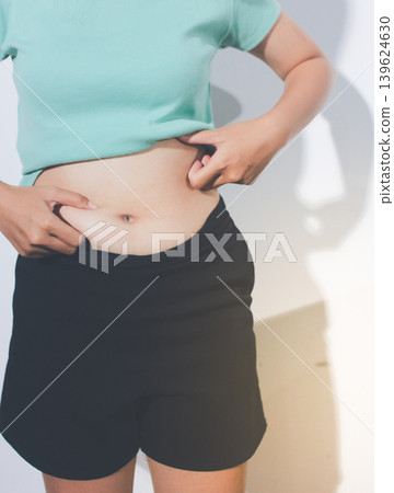 Flabby belly after pregnancy, overweight female body on gray background Flabby belly after pregnancy, overweight female body on gray background 139624630