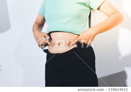 Flabby belly after pregnancy, overweight female body on gray background Flabby belly after pregnancy, overweight female body on gray background 139624632