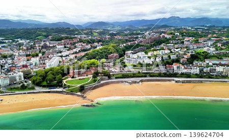Stunning Aerial View of a Charming Coastal Town Featuring a Golden Beach and Lush Green Hills Stunning Aerial View of a Charming Coastal Town Featuring a Golden Beach and Lush Green Hills 139624704