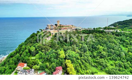 See an Aerial View of a Coastal Castle Surrounded by Lush Greenery and Natural Beauty See an Aerial View of a Coastal Castle Surrounded by Lush Greenery and Natural Beauty 139624742