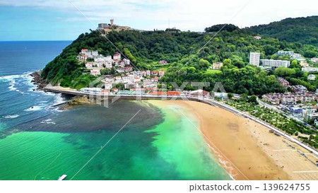 Stunning Aerial View of a Picturesque Coastal Village Surrounded by Lush Greenery and a Sandy Beach Stunning Aerial View of a Picturesque Coastal Village Surrounded by Lush Greenery and a Sandy Beach 139624755
