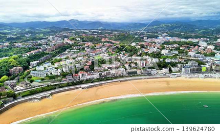 Stunning Aerial View of a Coastal Town Featuring a Beach and Majestic Mountains Nearby 139624780