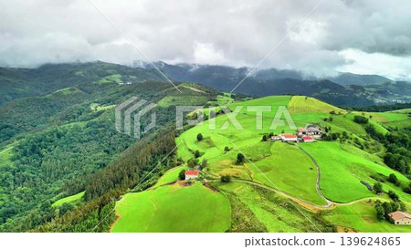A Stunning Aerial View of Lush Green Hills Accompanied by Beautiful Farmhouses Under a Cloudy Sky A Stunning Aerial View of Lush Green Hills Accompanied by Beautiful Farmhouses Under a Cloudy Sky 139624865