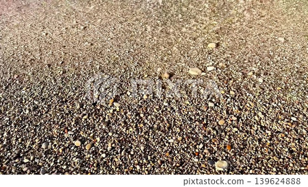 The beautiful textures of the ocean shoreline featuring colorful pebbles and gentle waves The beautiful textures of the ocean shoreline featuring colorful pebbles and gentle waves 139624888