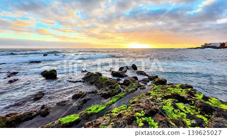 A breathtaking coastal sunset unfolds over the rugged rocks and gently rolling waves A breathtaking coastal sunset unfolds over the rugged rocks and gently rolling waves 139625027