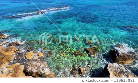 Experience the stunning coastal view with crystal clear waters and a rocky shoreline 139625081