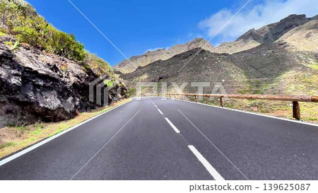 A picturesque and scenic coastal mountain road stretches under a clear blue sky A picturesque and scenic coastal mountain road stretches under a clear blue sky 139625087