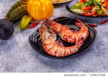 Grilled giant red prawns in a pan with fresh avocado, bell pepper, and salad on a stone table Grilled giant red prawns in a pan with fresh avocado, bell pepper, and salad on a stone table 139625386