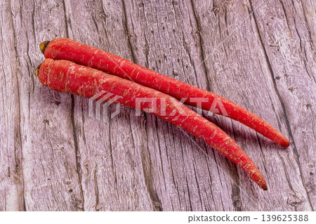 Two raw red carrots on a rustic wooden table. Fresh organic root vegetables. Two raw red carrots on a rustic wooden table. Fresh organic root vegetables. 139625388