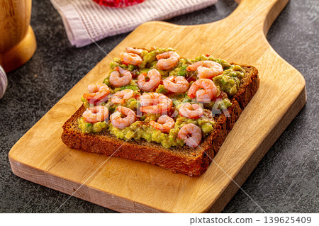 Shrimp and avocado toast on a wooden board with garlic, lime, and chili pepper Shrimp and avocado toast on a wooden board with garlic, lime, and chili pepper 139625409