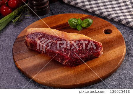 Raw beef steak on wooden cutting board, fresh basil, cherry tomatoes, culinary preparation 139625418