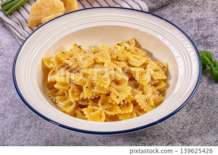 Freshly cooked farfalle pasta dish, parmesan cheese, cherry tomatoes, basil on rustic table Freshly cooked farfalle pasta dish, parmesan cheese, cherry tomatoes, basil on rustic table 139625426