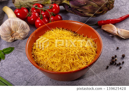 Uncooked vermicelli pasta in ceramic bowl, fresh garlic, ripe tomatoes, basil, artichoke, chili pepper Uncooked vermicelli pasta in ceramic bowl, fresh garlic, ripe tomatoes, basil, artichoke, chili pepper 139625428