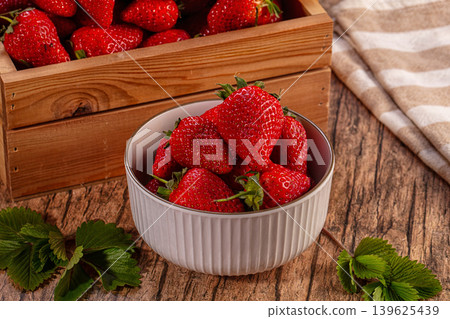 Fresh ripe strawberries in white bowl and wooden crate on rustic table Fresh ripe strawberries in white bowl and wooden crate on rustic table 139625439