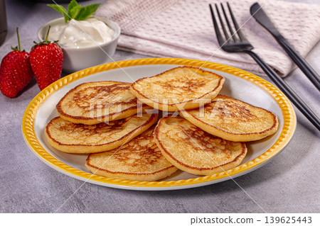 Homemade golden pancakes on plate with fresh strawberries and sour cream 139625443