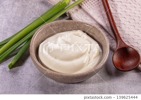Sour cream in ceramic bowl with fresh green onions and wooden spoon Sour cream in ceramic bowl with fresh green onions and wooden spoon 139625444