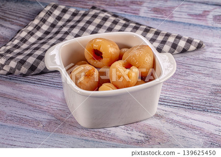Peeled lychee fruit in white ceramic bowl on rustic wooden table with checkered cloth Peeled lychee fruit in white ceramic bowl on rustic wooden table with checkered cloth 139625450