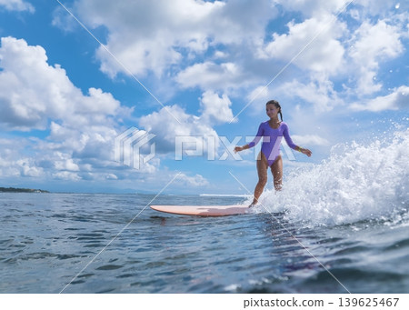Young Surfer Balancing Gracefully Under Ominous Clouds In Ocean Young Surfer Balancing Gracefully Under Ominous Clouds In Ocean 139625467