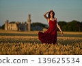 Woman rye field red dress. Happy woman in a long red dress in a beautiful cornfield. Old caste ruins in the background 139625534