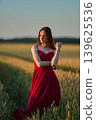 Woman rye field red dress. Happy woman in a long red dress in a beautiful cornfield. Old caste ruins in the background 139625536