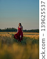 Woman rye field red dress. Happy woman in a long red dress in a beautiful cornfield. Old caste ruins in the background 139625537
