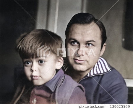 A vintage portrait of a father and son. The son is looking at something with fascination. Retro photo, 1973 A vintage portrait of a father and son. The son is looking at something with fascination. Retro photo, 1973 139625569