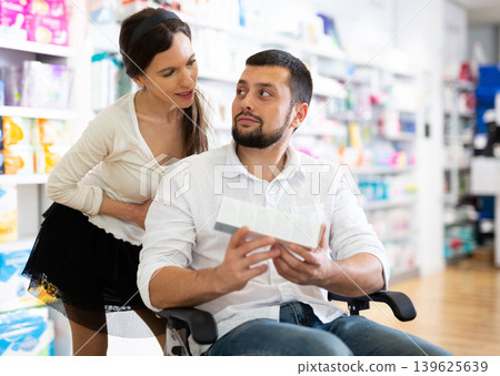 Man in wheelchair and woman in drugstore 139625639