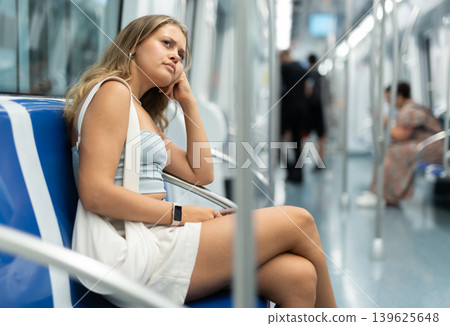 Young woman sitting in subway car with phone Young woman sitting in subway car with phone 139625648