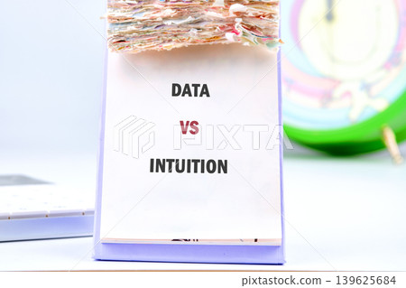 A white desk calendar with many pages displays DATA VS INTUITION in bold letters 139625684