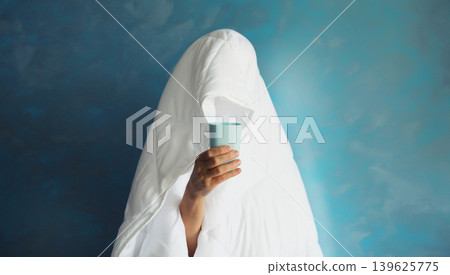 Lazy woman waking up after sleeping covered with white blanket holds cup of coffee in the morning Lazy woman waking up after sleeping covered with white blanket holds cup of coffee in the morning 139625775